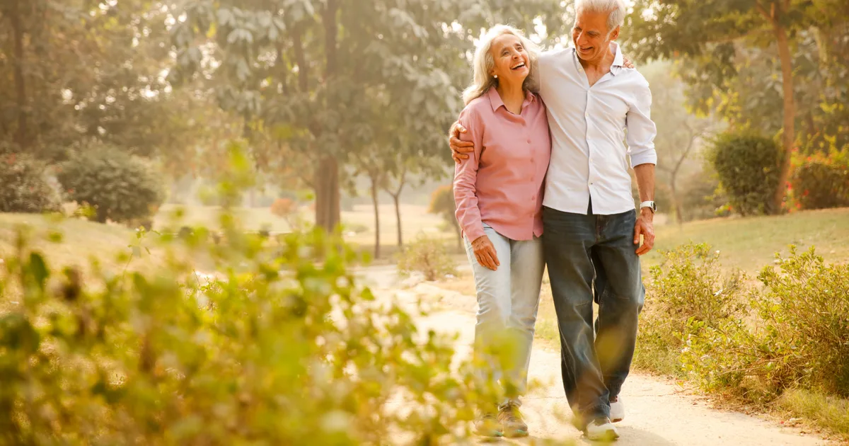 Pareja mayor paseando de la mano por un parque soleado una mañana de otoño