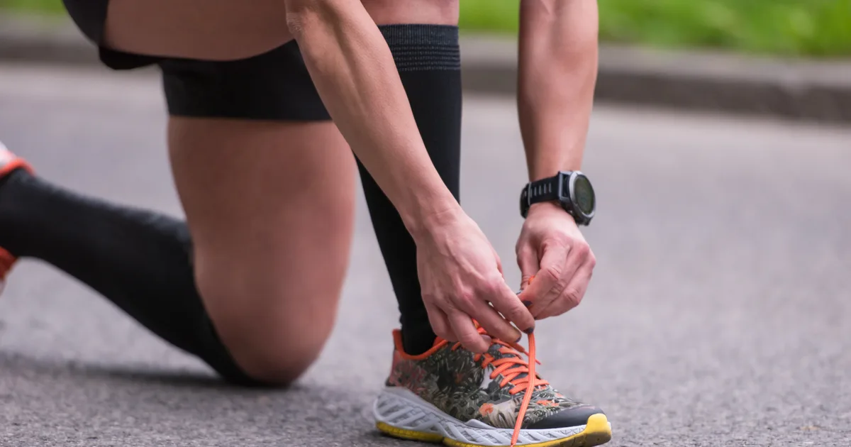 Mujer atándose las zapatillas de correr en un parque de la ciudad por la mañana