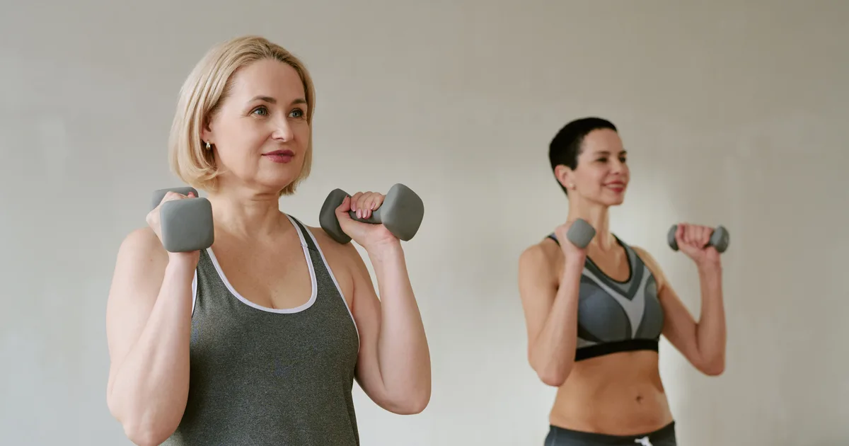 Dos mujeres de mediana edad entrenando fuerza con mancuernas